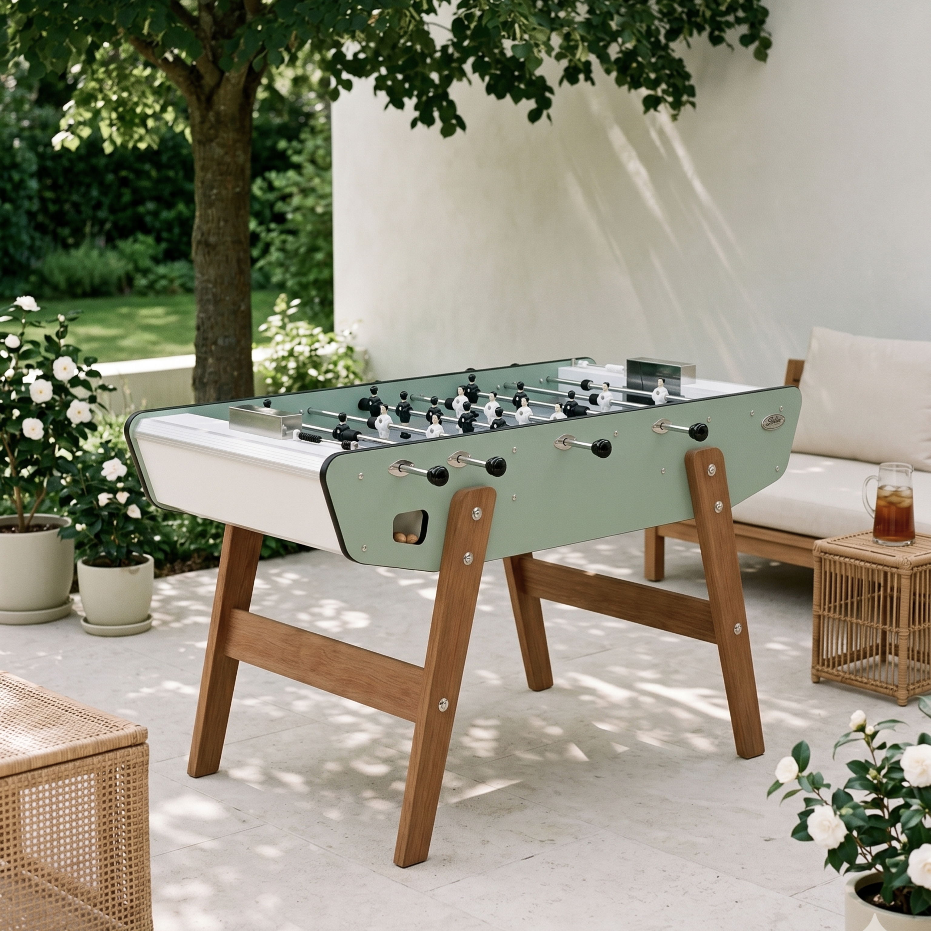 Baby-foot d'extérieur Stella Home Outdoor vert eucalyptus installé sur une terrasse, structure en HPL ultra-résistante pour profiter du jeu en plein air dans le jardin toute l'année.