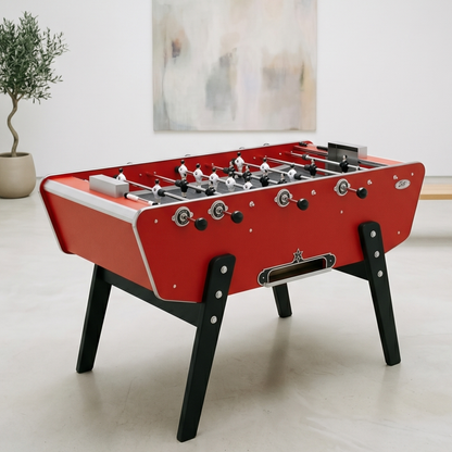 Baby-foot Stella Star rouge avec caisse style bateau installé dans un salon convivial, le modèle iconique des cafés français pour une ambiance de jeu authentique et chaleureuse.