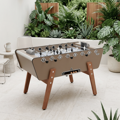 Baby-foot d'extérieur Stella Champion Outdoor taupe installé sur une terrasse, coloris élégant et naturel alliant design contemporain et robustesse pour une utilisation en plein air toute l'année.