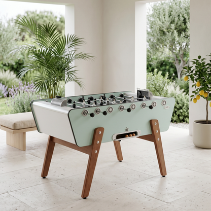 Baby-foot d'extérieur Stella Champion Outdoor vert eucalyptus installé sur une terrasse, design élégant et robuste pour profiter du jeu en plein air dans un jardin ou un espace extérieur moderne.