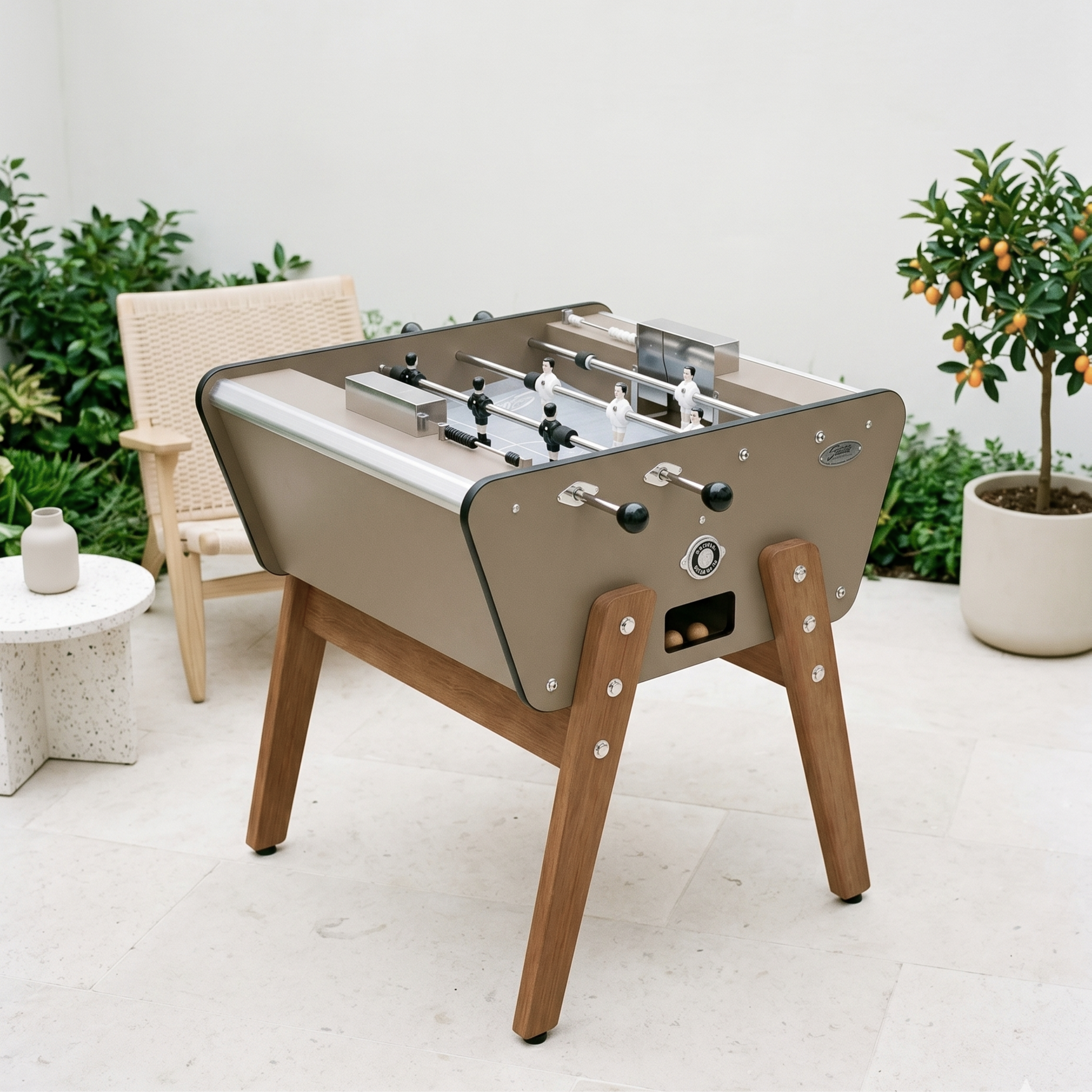 Baby-foot 2 joueurs Stella Toi&Moi Outdoor taupe installé sur une terrasse, coloris élégant et intemporel pour profiter du jeu en duo dans le jardin toute l'année.