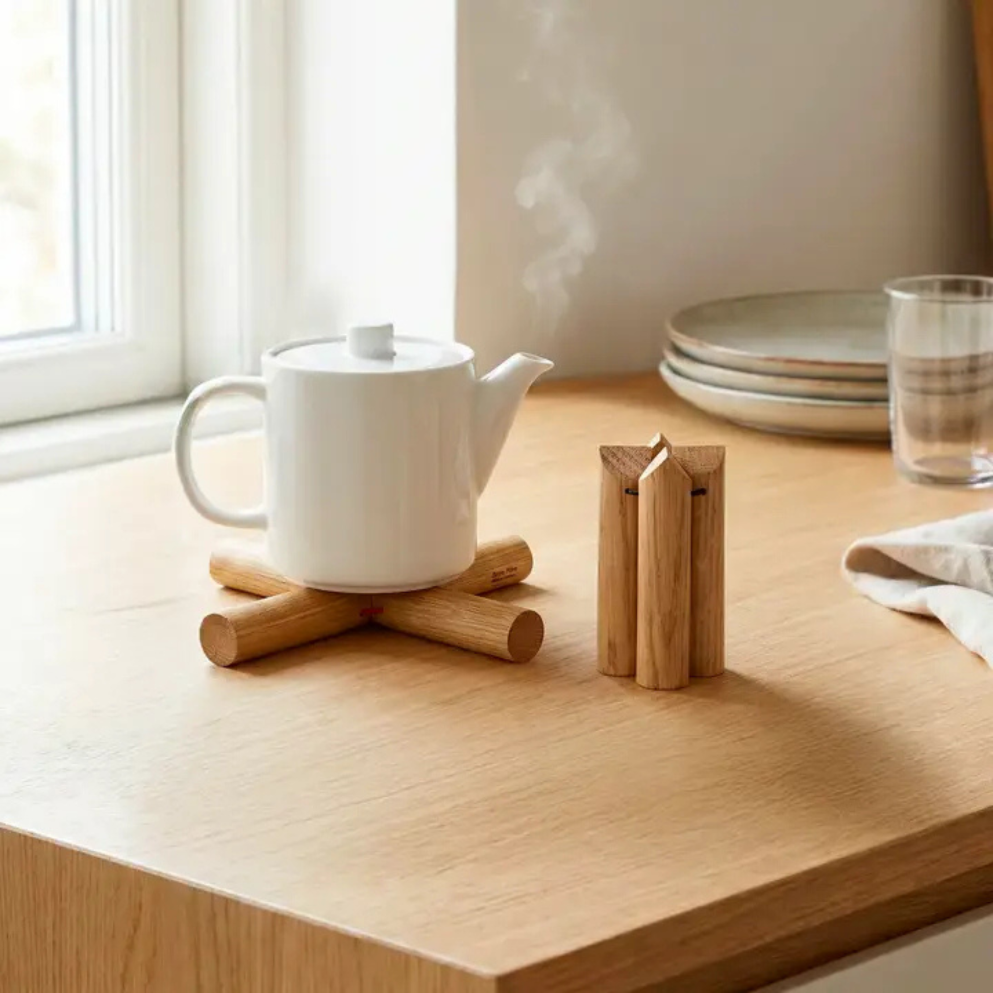 Petite cafetière italienne posée sur un dessous de plat design en bois naturel pour un petit-déjeuner minimaliste.