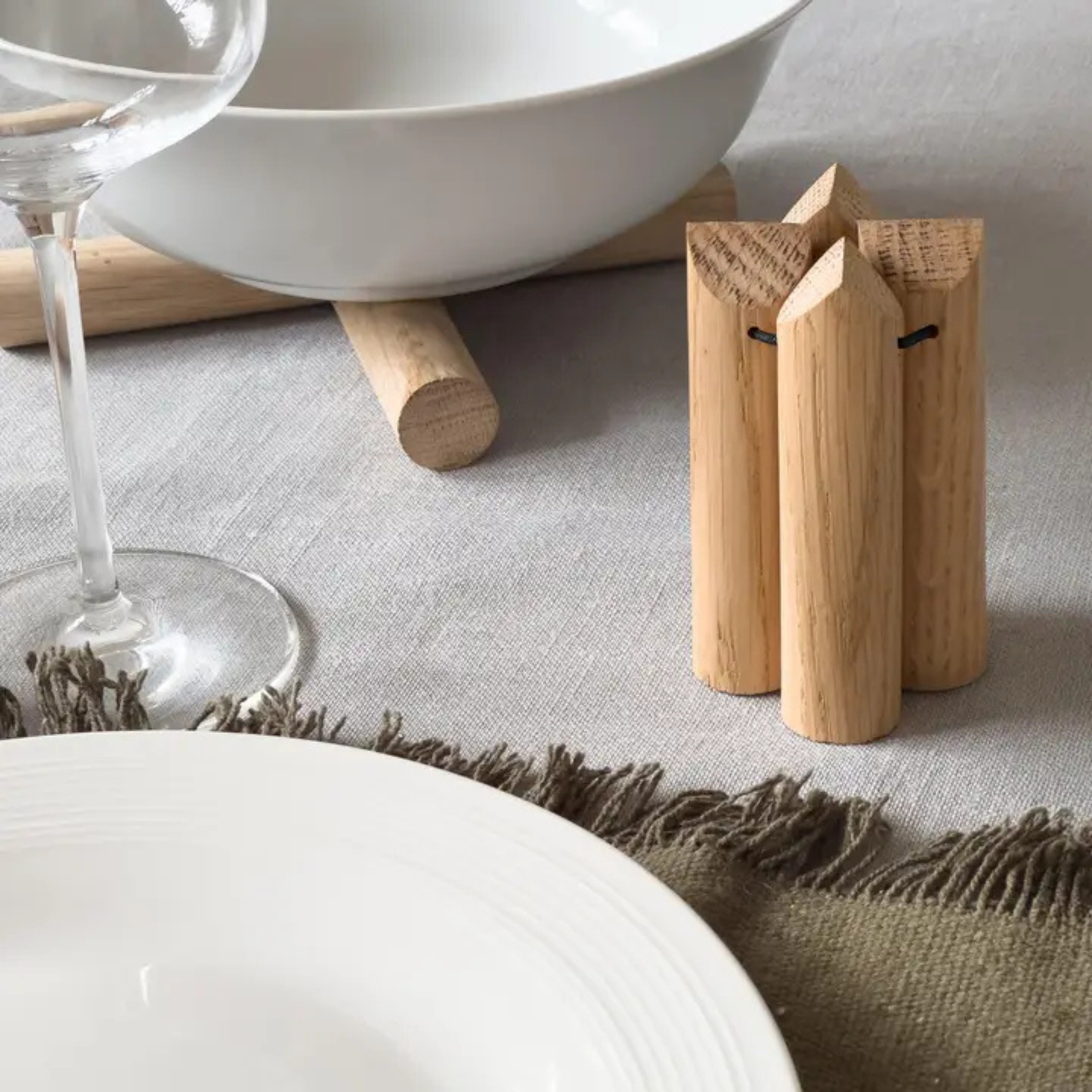 Dessous de plat en hêtre replié sur lui-même montrant son format compact pour un rangement facile dans un tiroir.