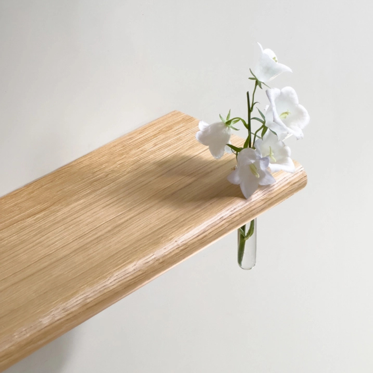 Étagère murale Berge en chêne massif de 70 cm au design architectural et épuré, fixée sur un mur clair avec des livres et objets de décoration.