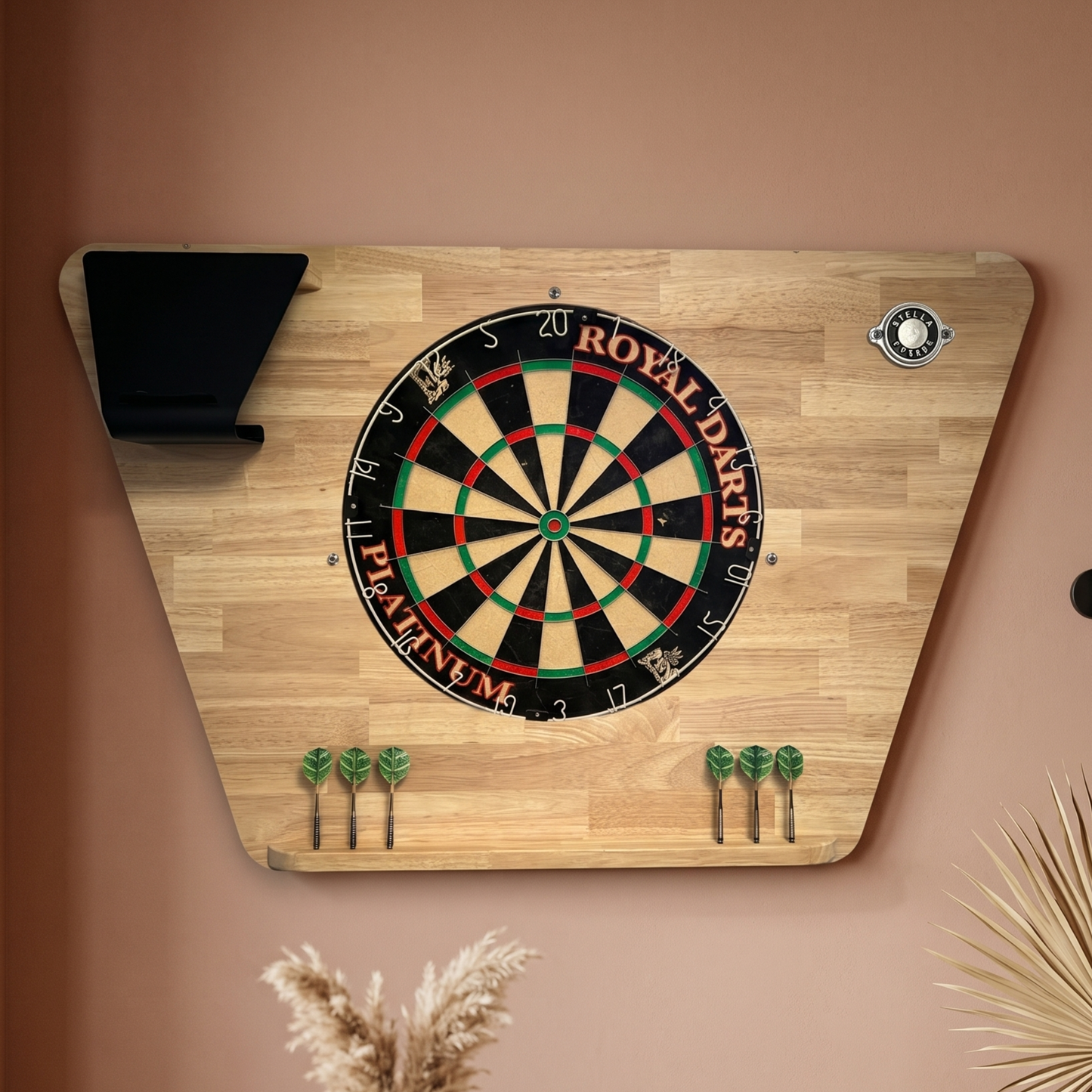 Pack support de fléchettes Stella Hévéa avec cible traditionnelle en sisal accroché au mur d'un salon, bois naturel noble et cible artisanale pour une expérience de jeu authentique en intérieur.